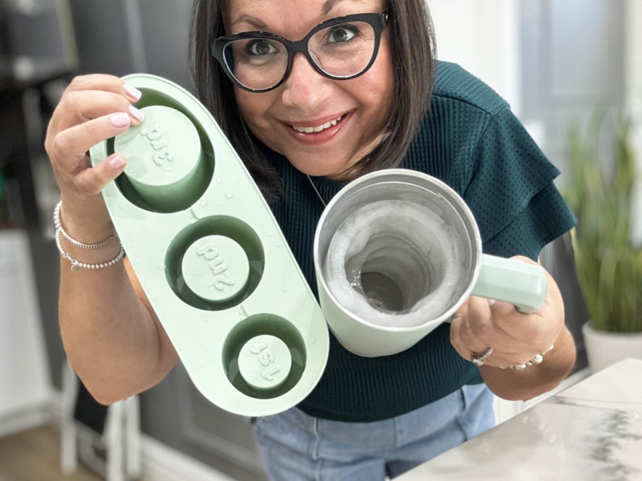 woman holding up silicone ice tray and tumbler with ice cylinders inside