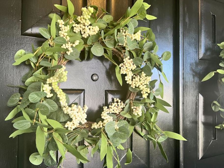 Close up of artificial green eucalyptus wreath on black door
