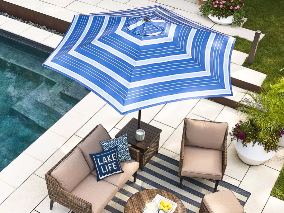 blue striped patio umbrella over furniture in backyard