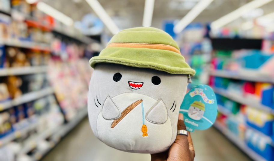 a womans hand holding a Squishmallows Gordon the Grey Shark Bucket Hat Fishing Rod
