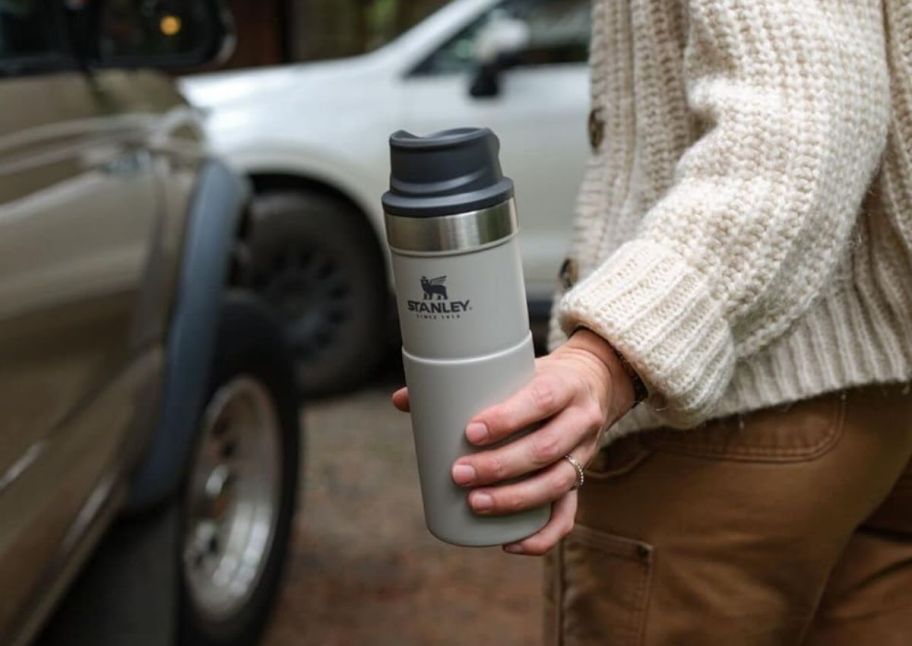 a woman holding a stanley travel tumbler