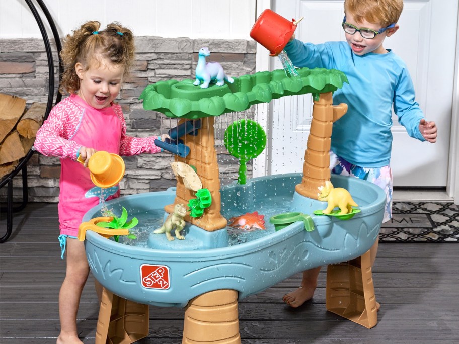 two kids playing at dinosaur themed water table