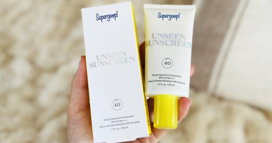 hand holding a box and tube of supergoop sunscreen