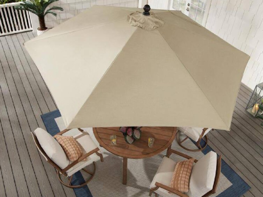 Tan patio umbrella with patio set underneath it