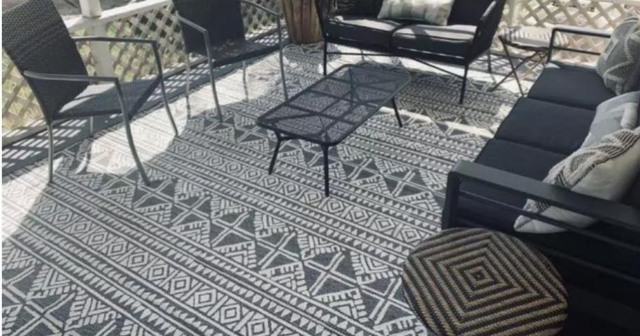 A Threshold Outdoor Rug Tasseled in Charcoal on a patio 