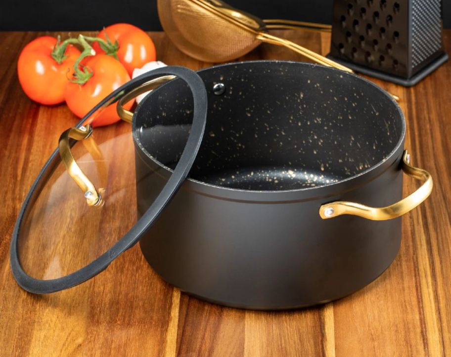 a black 5quart stock pot with a glass lid and gold handles