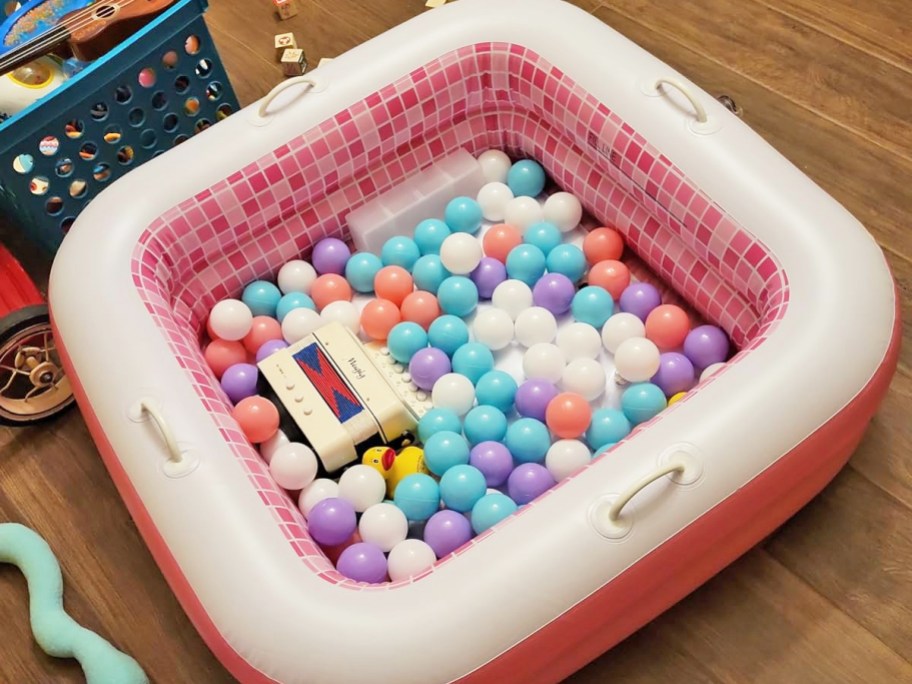 pink and white inflatable pool filled with plastic balls