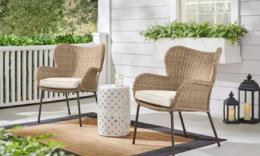 Two brown seating patio chairs with a rug underneath