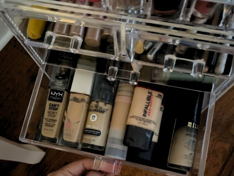 Hand opening a drawer on an acrylic makeup organizer