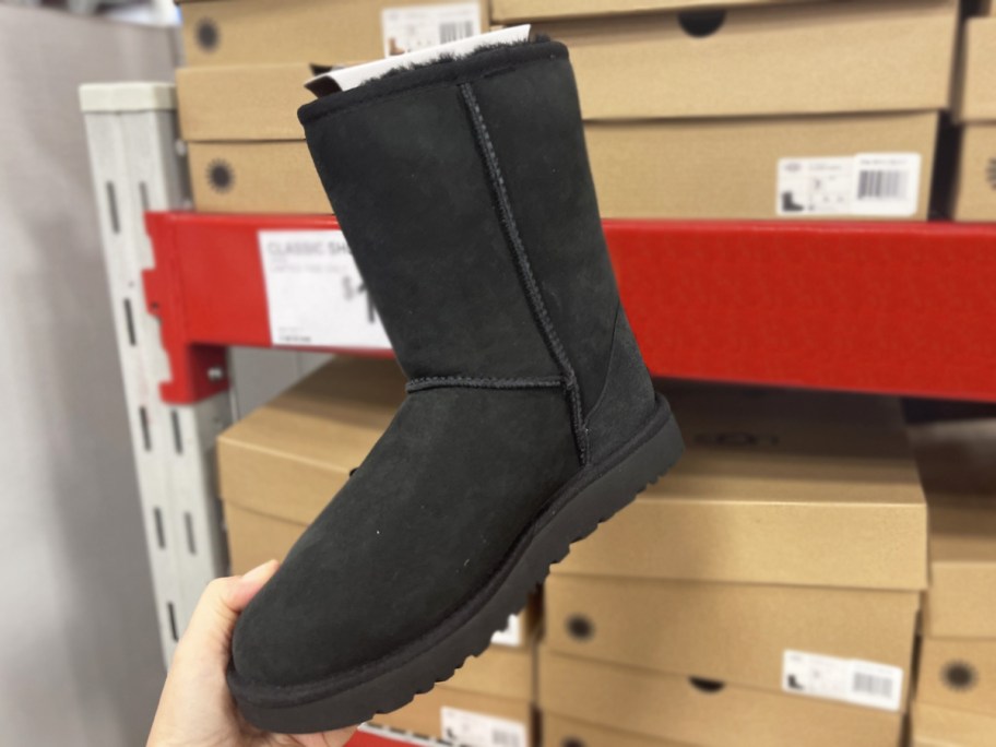 hand holding up a black classic ugg boot in store