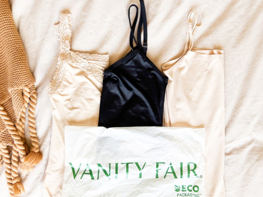 three nude and black camis on bed with vanity fair shipping package on top of them