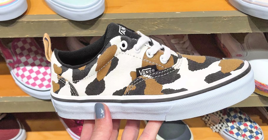 hand holding up a white, black, and brown vans sneaker