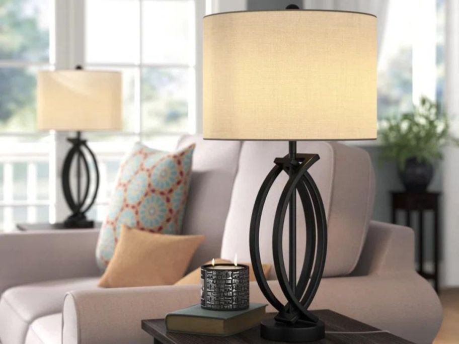 An end table next to a couch with a Three Posts Burholme Metal Table Lamp on it