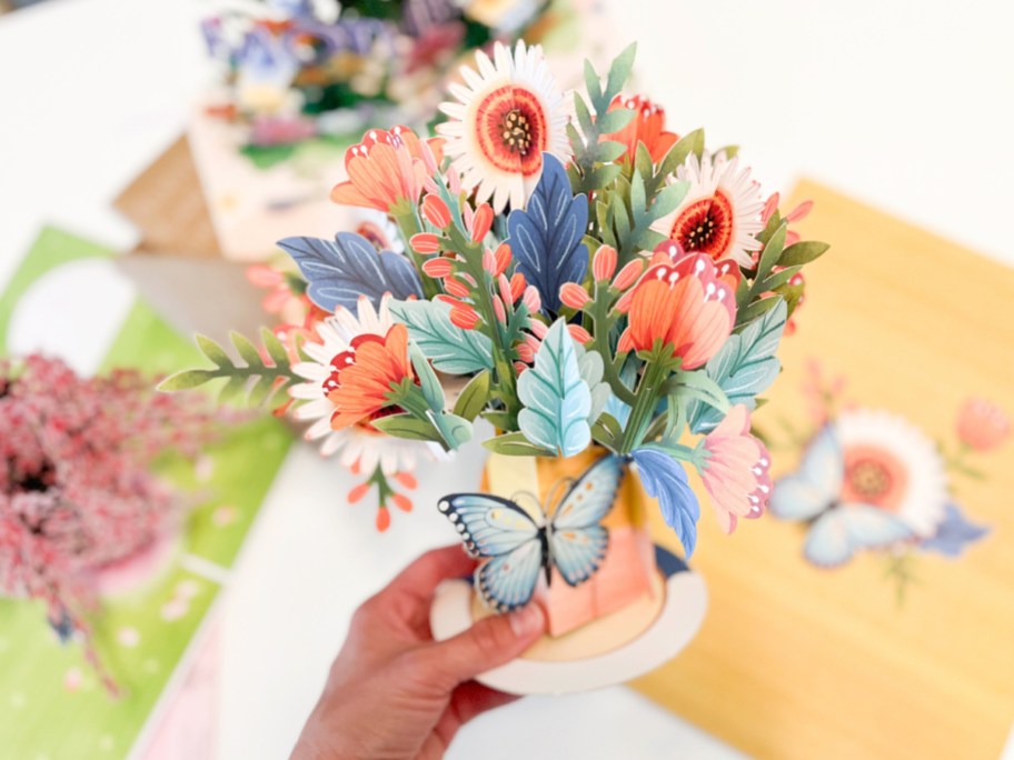 Woman holding paperflower bouquet in front of other flower cards