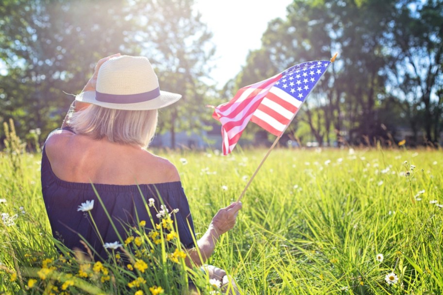 A woman sitting outdoors and holding an american flag