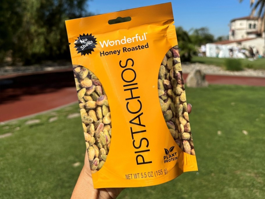 holding up a yellow bag of Wonderful Pistachios in Honey Roasted flavor