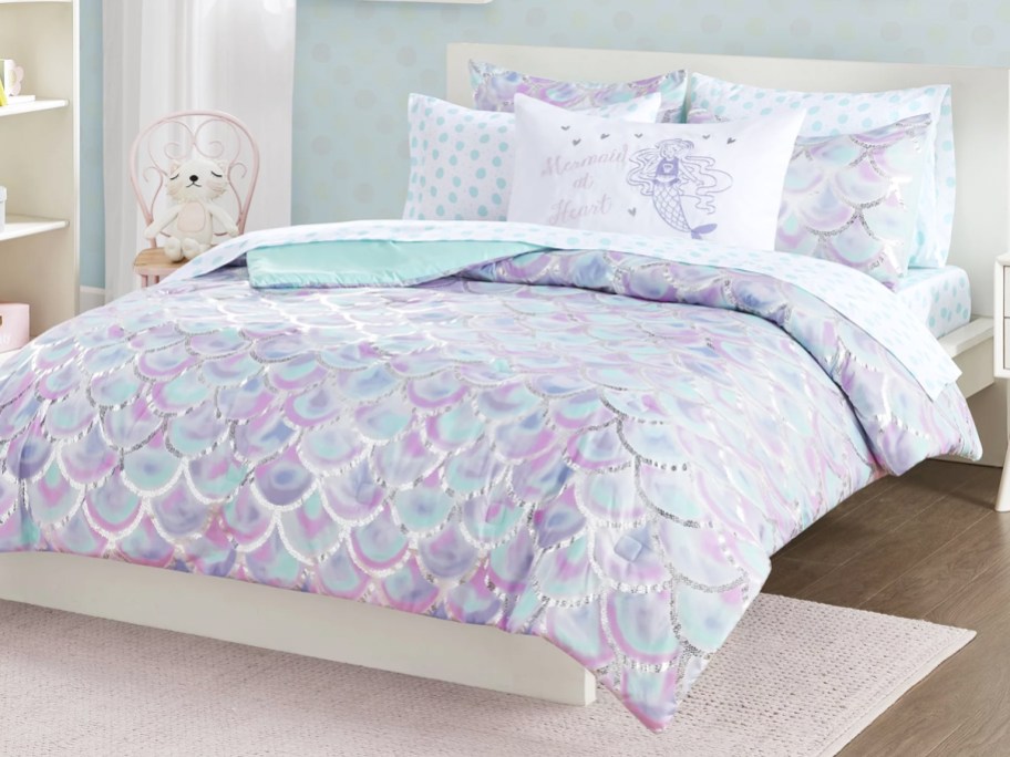 purple and blue seashell print comforter on bed with mermaid pillows