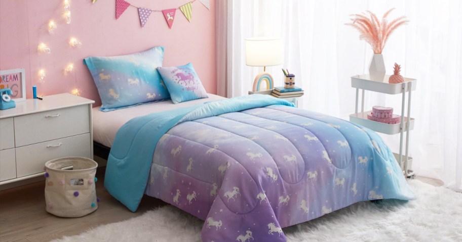 blue and purple unicorn comforter set on bed with string lights on wall above it