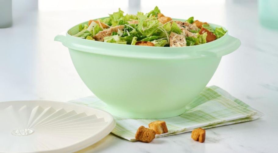 a large pastel green tupperware bowl filled with salad