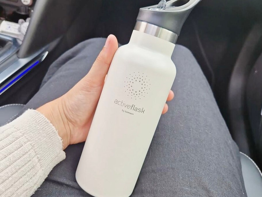 hand holding white cream bemax stainless steel water bottle