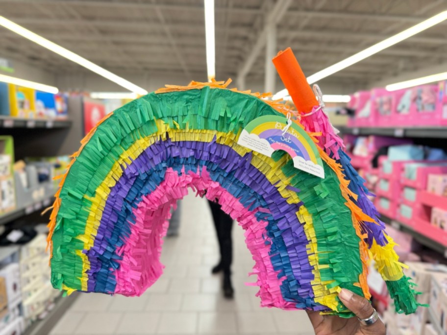 hand holding a rainbow pinata in a store
