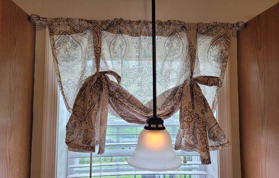valance hanging from window with hanging light in front of it
