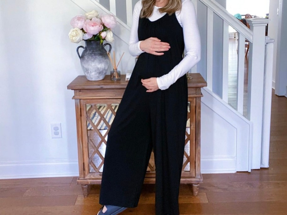 woman in black jumpsuit holding belly