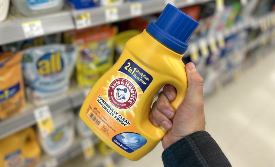 a mans hand holding a bottle of arm and hammer liquid laundry detergent