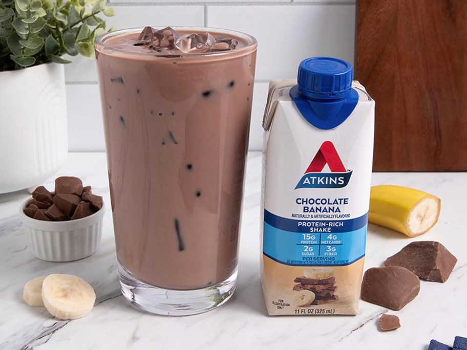 atkins protein shake next to cup filled with shake on table