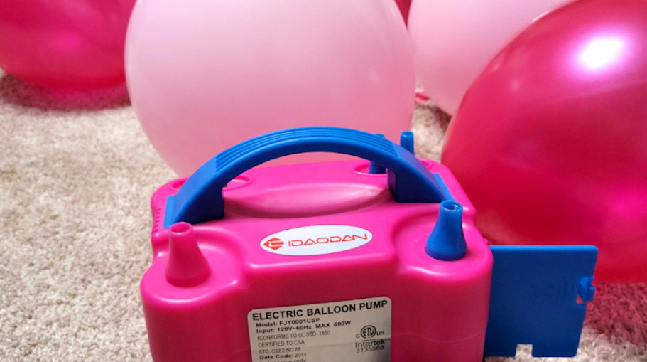 pink and blue electric balloon pump with pink balloons behind it