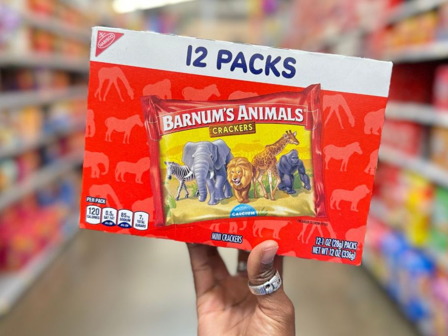Barnum's Original Animal Crackers, 12 - 1 oz Snack Packs being held by hand in store aisle