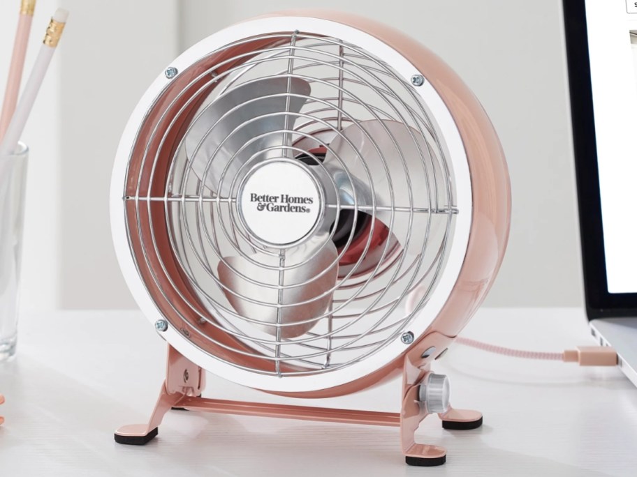 small pink round drum retro style table fan on a desk