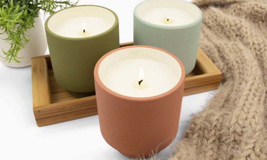 green, orange, and light blue ceramic candles sitting on table next to blanket