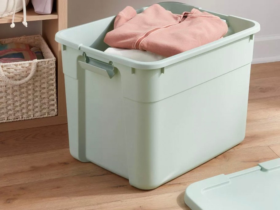 green storage tote with sweaters inside 