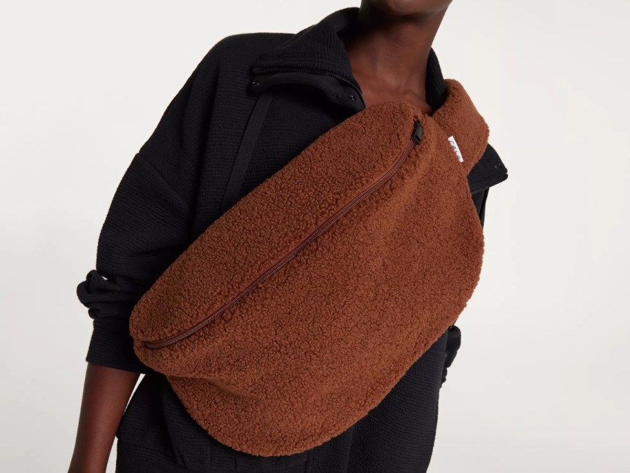 woman wearing a large brown sherpa sling bag and black top