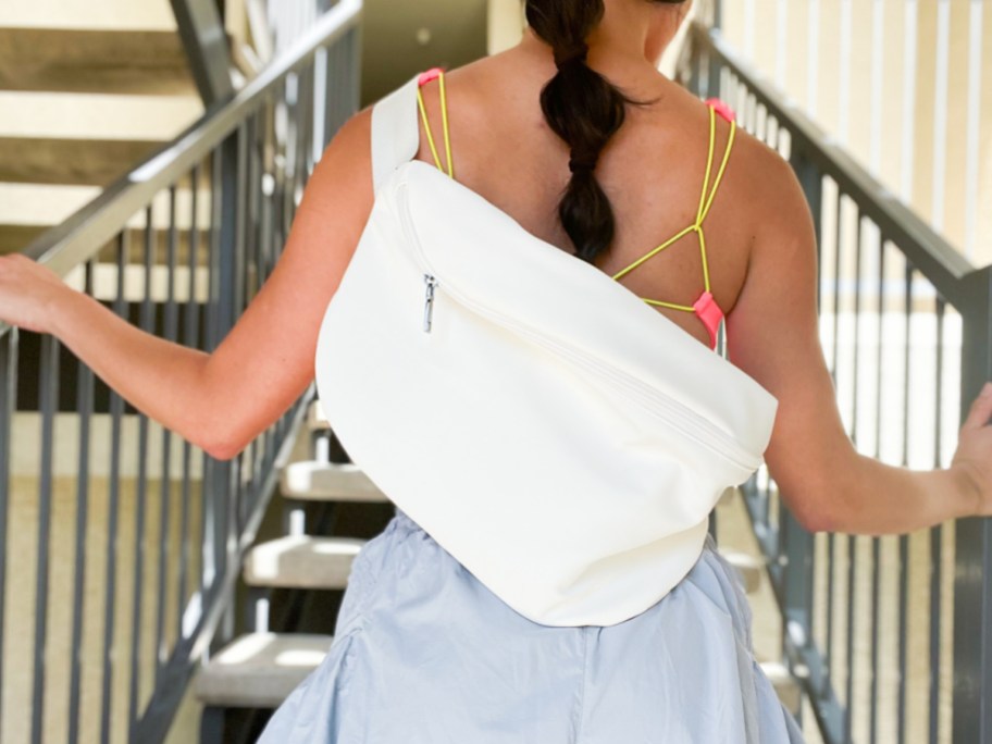 woman on stairs wearing white sling backpack