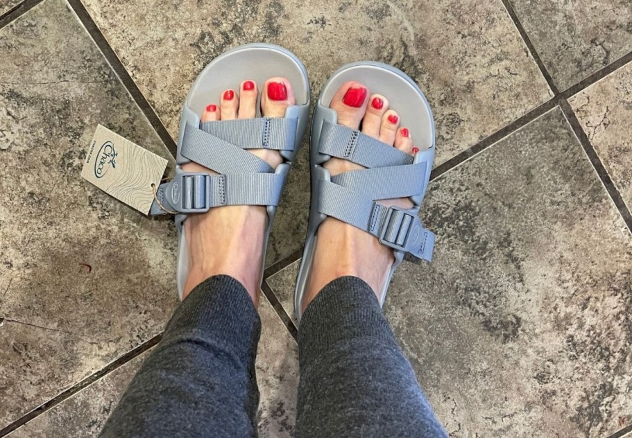 womans pedicured feet with painted toenails inside a pair of gray chacos sandals
