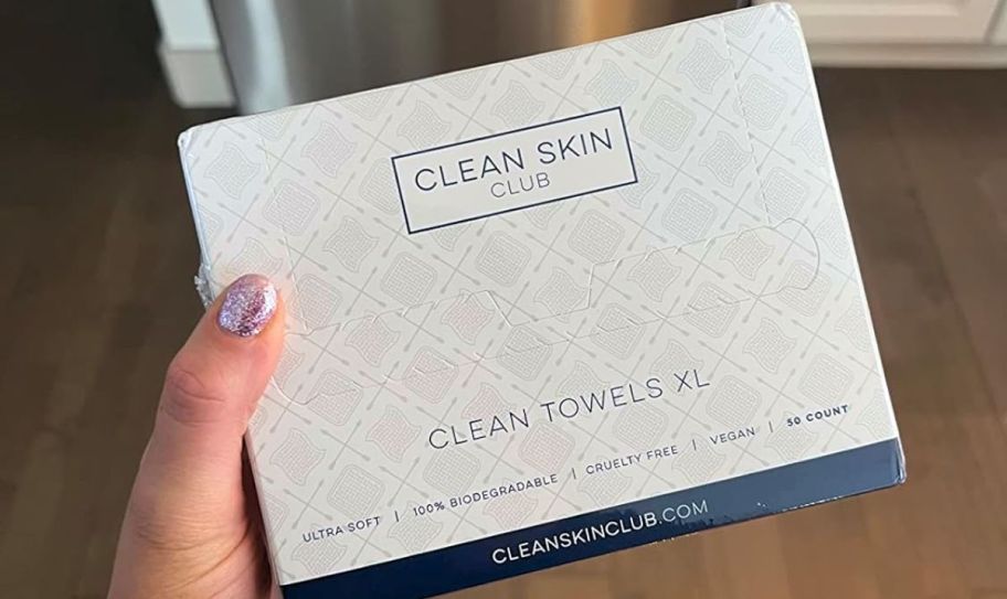 a womans hand holding a box of clean skin club XL face towels