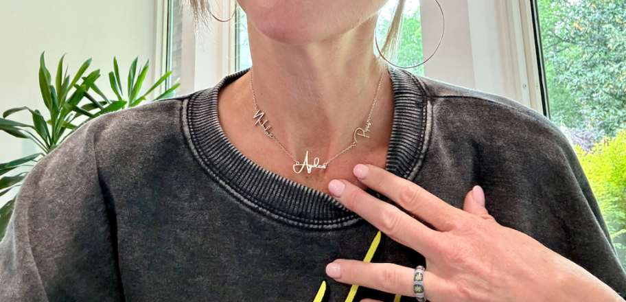 woman pointing to the silver name necklace around her neck