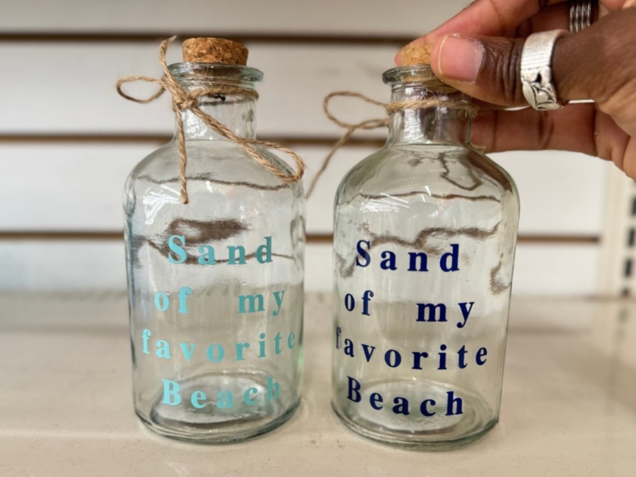 clear glass bottles with cork stoppers that say "sand of my favorite beach"
