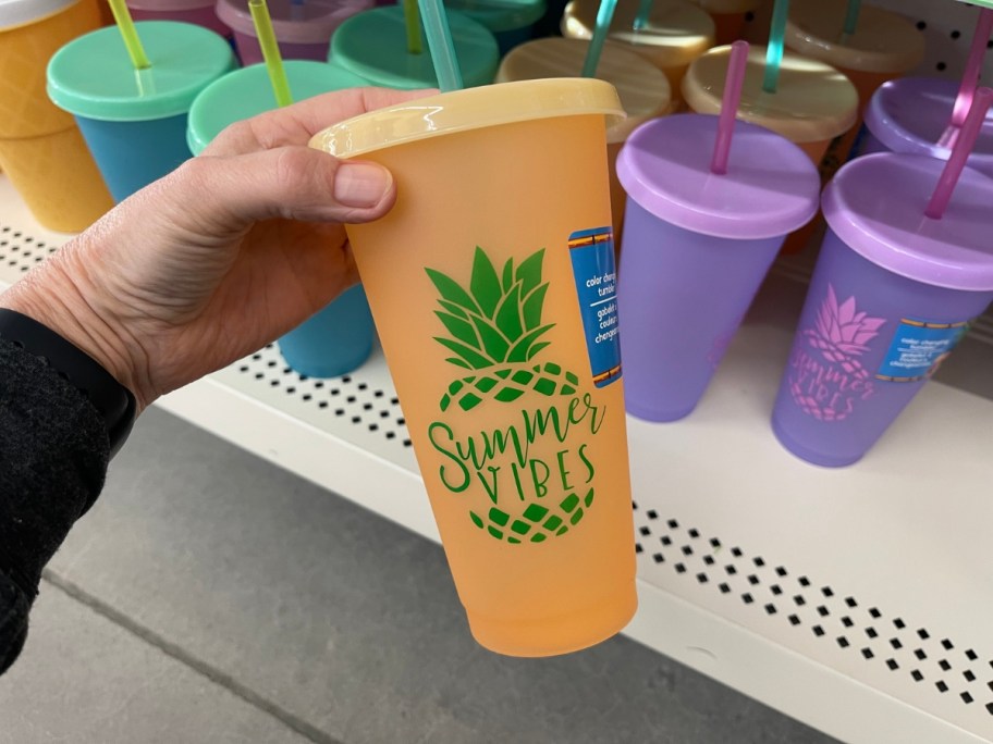 hand holding an orange straw tumbler that has a pineapple and says "summer vibes"