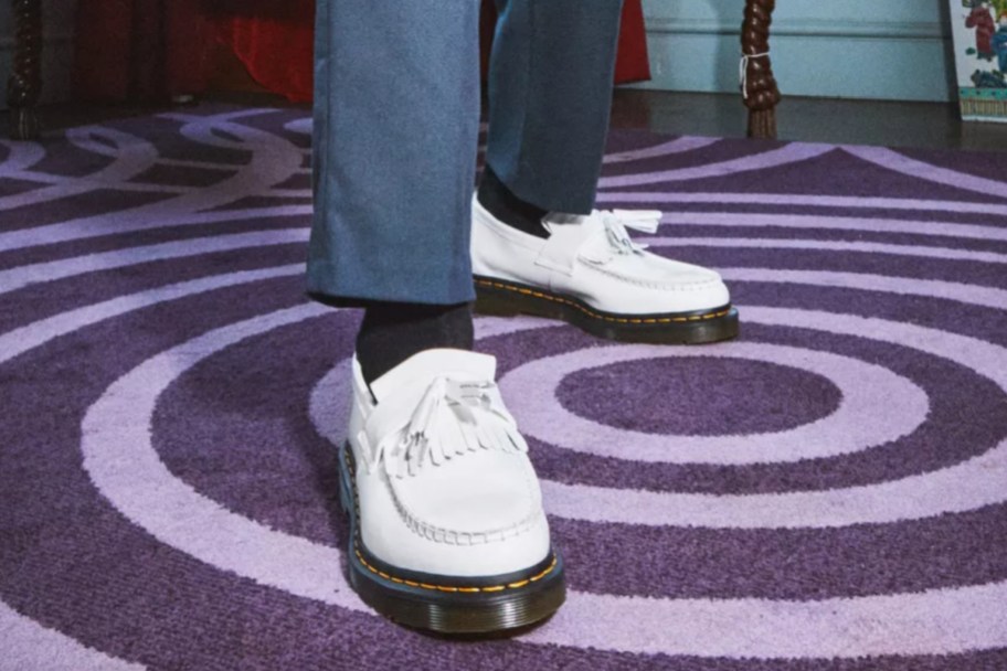 person wearing white loafers on purple rug