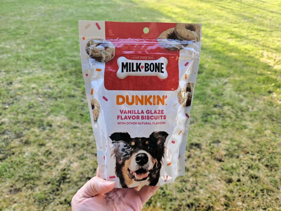 bag of dunkin dog treats held in hand in front of a lawn