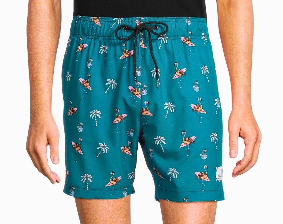 a man wearing a pair of teal novelty print swim trunks