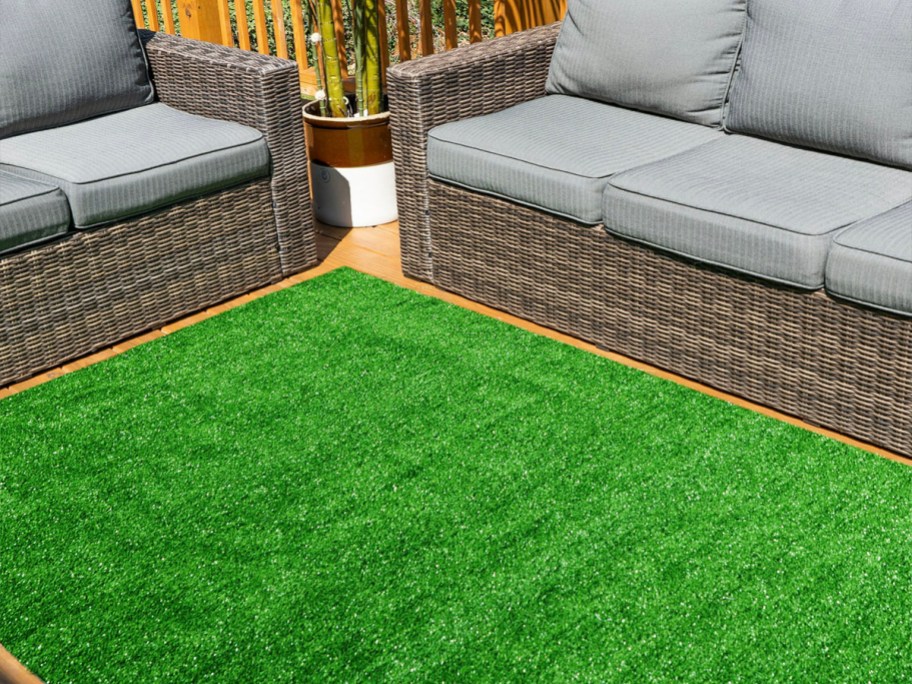 artifical turf area rug in between two gray couches