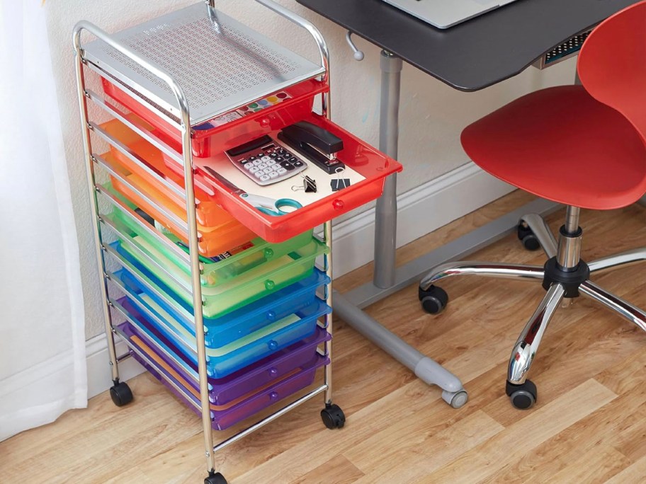 rainbow colored 10 drawer storage cart next to stool and desk 