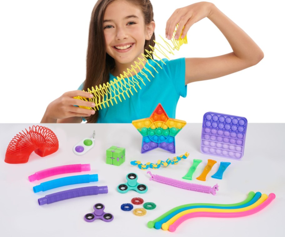 girl in a blue top playing with an assortment of colorful fidget toys