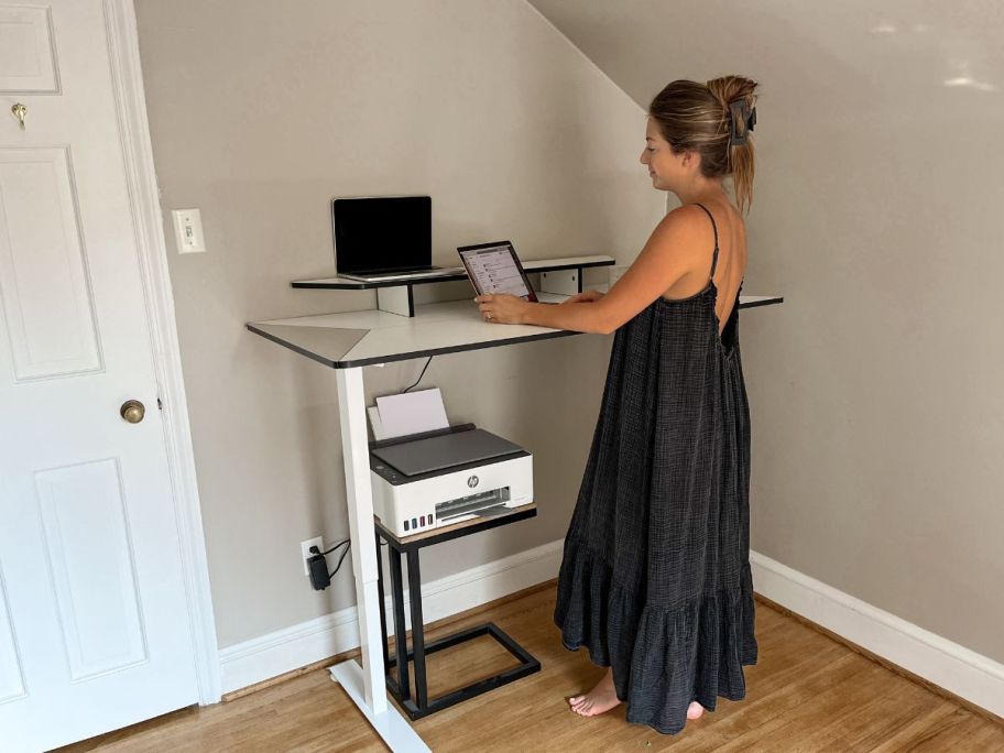 woman using a laptop while standing at a desk