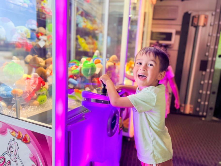 little boy playing with a claw machine