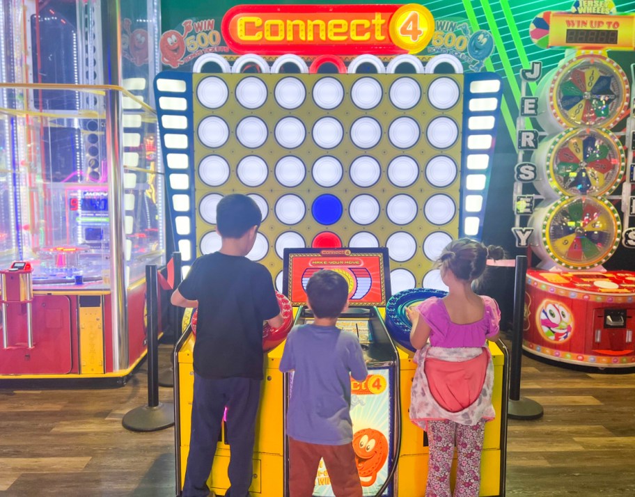 three kids standing at giant connect 4 